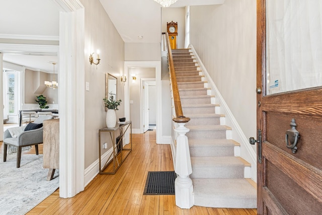 stairs featuring visible vents, crown molding, hardwood / wood-style flooring, and an inviting chandelier