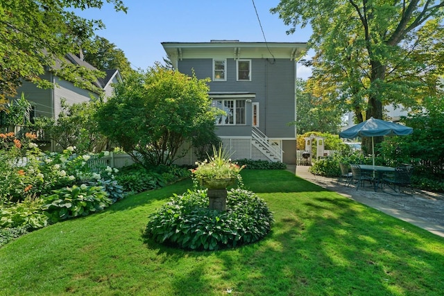 rear view of house with a yard, stairs, and a patio