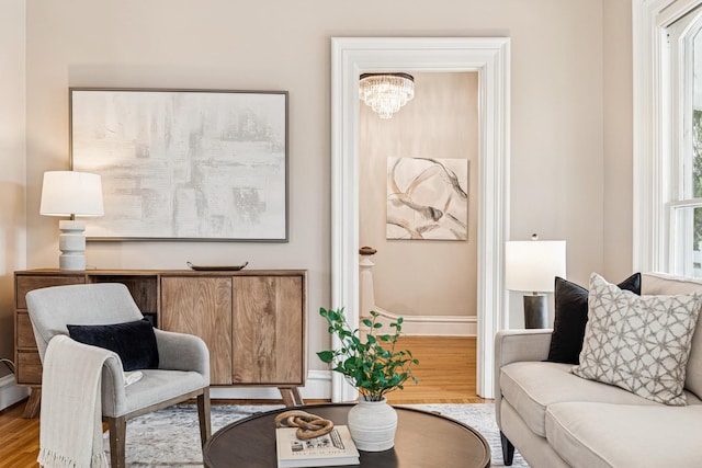 living area featuring an inviting chandelier, wood finished floors, and baseboards