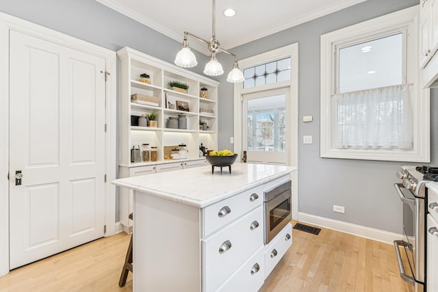 kitchen with white cabinets, light wood-style flooring, a center island, and appliances with stainless steel finishes