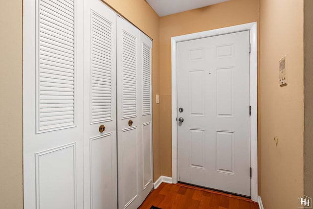 doorway featuring dark wood-type flooring and baseboards