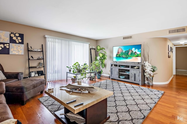 living room featuring visible vents, baseboards, and wood finished floors