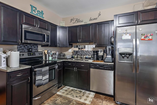 kitchen featuring light stone countertops, appliances with stainless steel finishes, decorative backsplash, and a sink