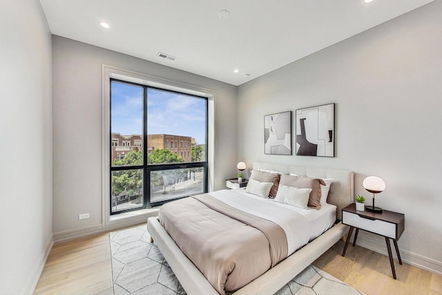 bedroom with visible vents, baseboards, light wood finished floors, and multiple windows