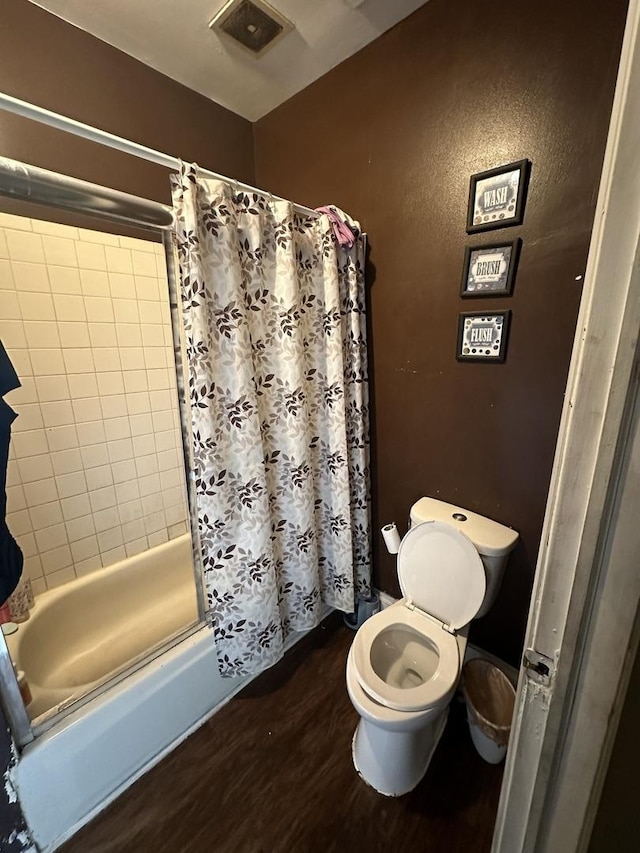 bathroom featuring a shower with curtain, visible vents, toilet, and wood finished floors