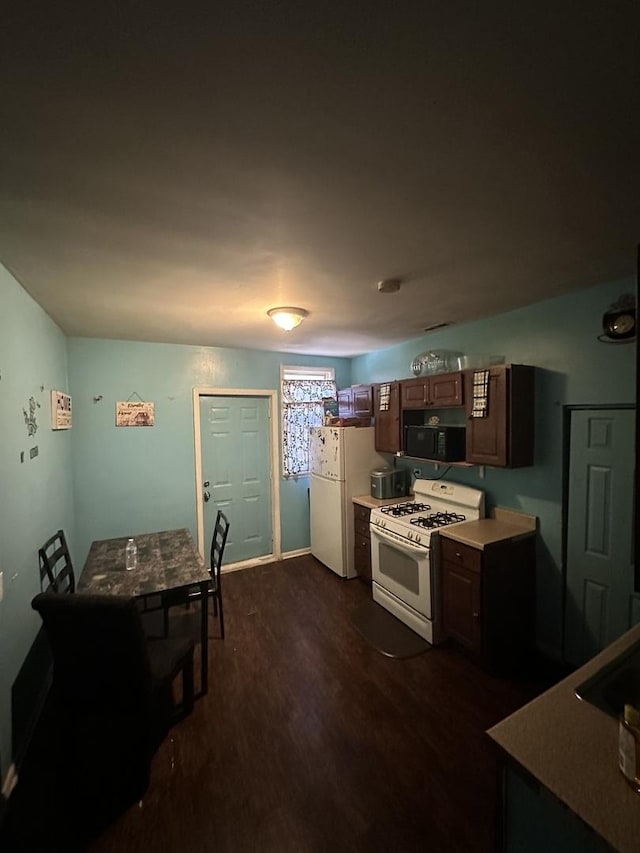 kitchen featuring white appliances, dark brown cabinets, dark wood-type flooring, and light countertops