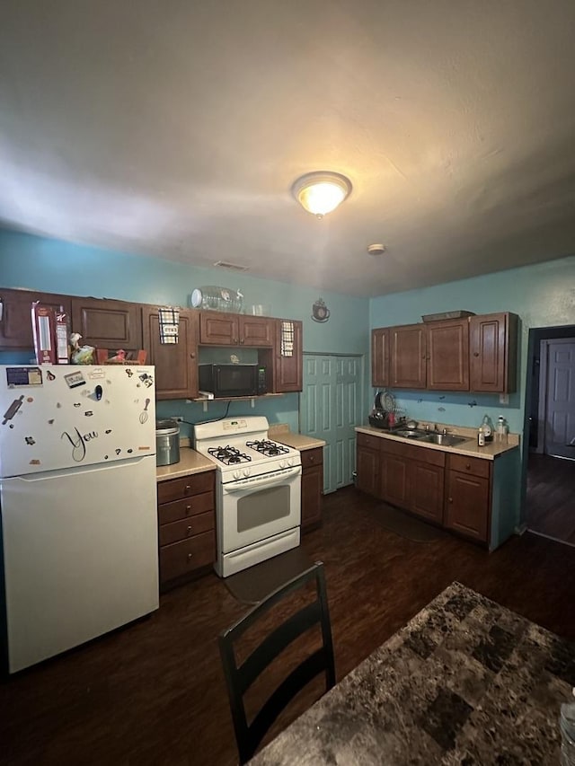 kitchen with dark wood-style floors, light countertops, white appliances, and a sink