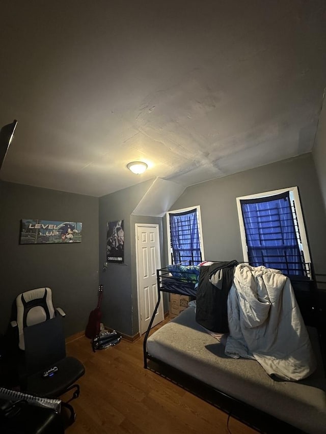 bedroom with vaulted ceiling and wood finished floors