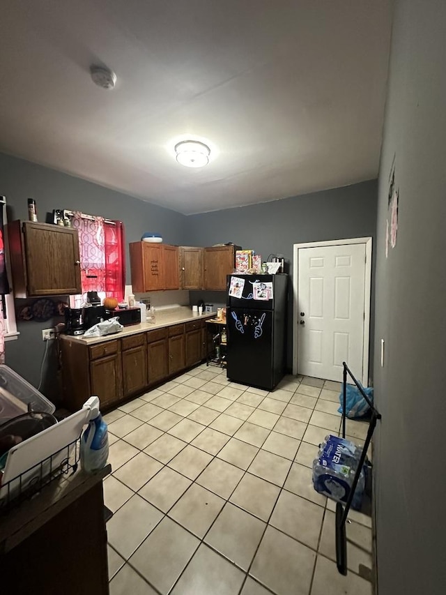 kitchen with freestanding refrigerator, light countertops, and light tile patterned floors