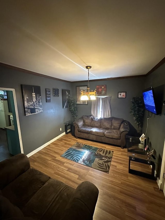 living room with an inviting chandelier, baseboards, wood finished floors, and ornamental molding