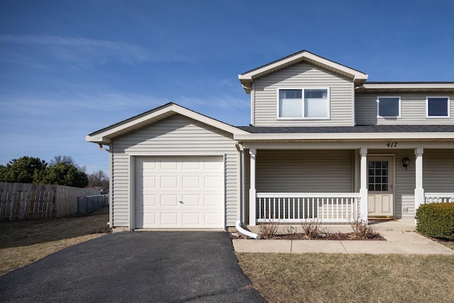 traditional home with an attached garage, fence, covered porch, and driveway