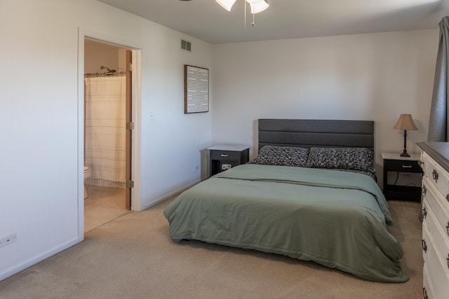 bedroom with visible vents, light colored carpet, ensuite bathroom, and baseboards