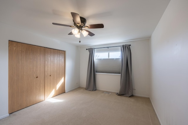 unfurnished bedroom featuring visible vents, a ceiling fan, a closet, baseboards, and light colored carpet