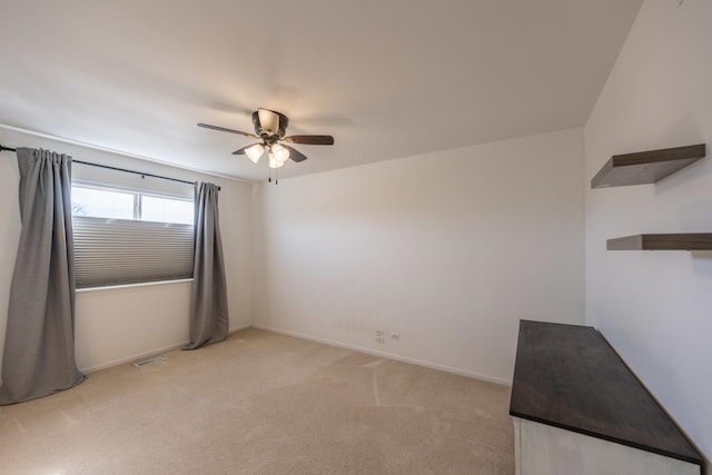 unfurnished room featuring light carpet, baseboards, and ceiling fan