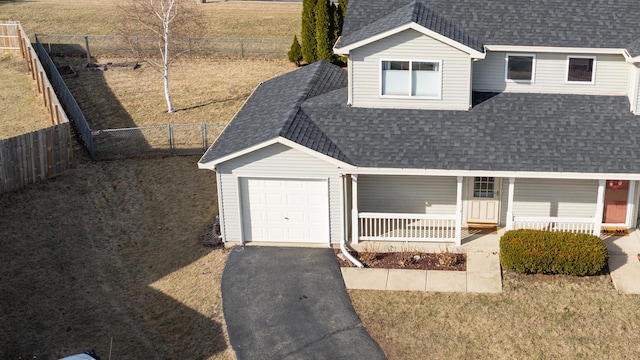 view of front of property with aphalt driveway, roof with shingles, covered porch, a garage, and a fenced backyard