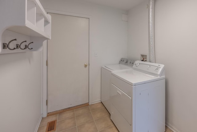 washroom featuring light tile patterned floors, laundry area, washer and dryer, and visible vents