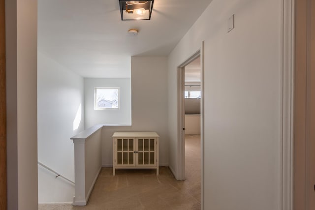 hall featuring carpet flooring, an upstairs landing, and baseboards