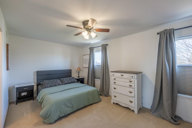 bedroom with multiple windows, light carpet, and a ceiling fan