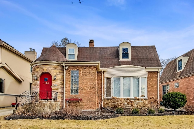 view of front of house with brick siding, stone siding, a chimney, and a shingled roof