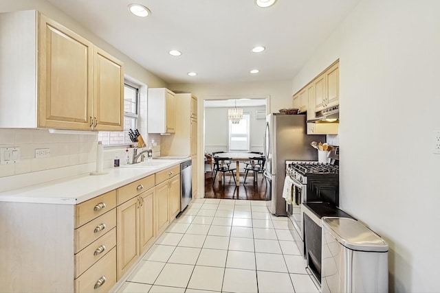 kitchen with under cabinet range hood, tasteful backsplash, appliances with stainless steel finishes, and light brown cabinets