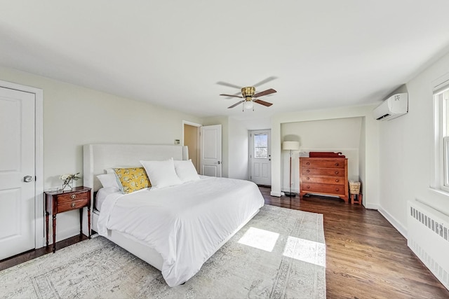 bedroom with a ceiling fan, a wall mounted AC, wood finished floors, radiator heating unit, and baseboards