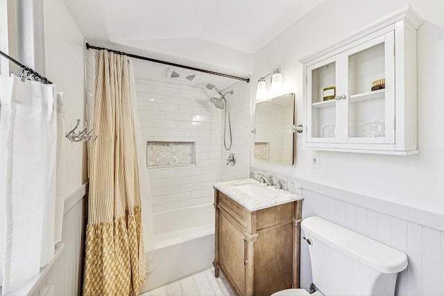 full bathroom featuring toilet, lofted ceiling, wainscoting, vanity, and shower / bathtub combination with curtain