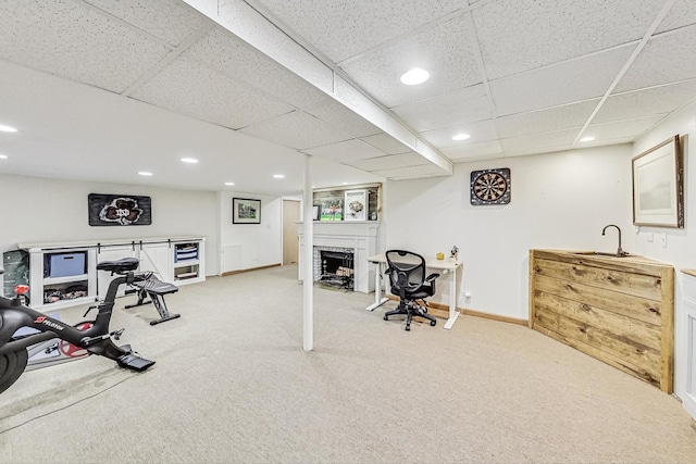 exercise area with light colored carpet, a fireplace, baseboards, and a sink