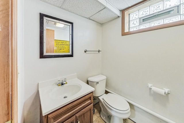 bathroom with toilet, vanity, and a paneled ceiling