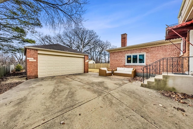 exterior space featuring brick siding, a detached garage, fence, outdoor lounge area, and an outbuilding