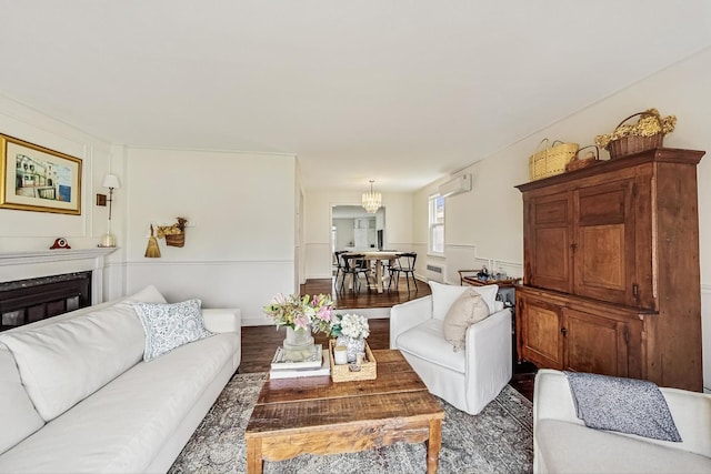 living area with a glass covered fireplace, wood finished floors, and a wall unit AC