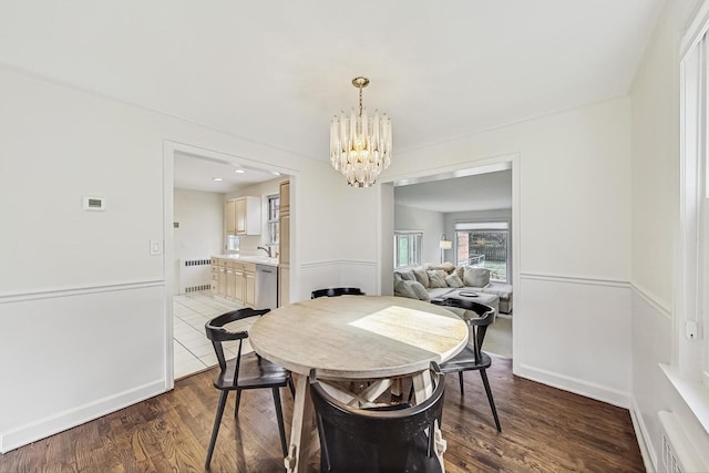 dining room featuring dark wood finished floors, a chandelier, radiator, and baseboards