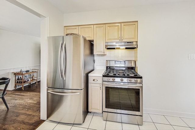 kitchen featuring light brown cabinetry, under cabinet range hood, backsplash, appliances with stainless steel finishes, and light countertops