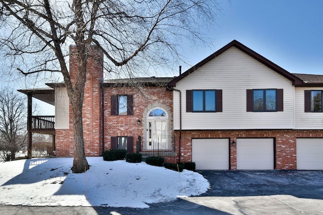 split foyer home featuring a garage, brick siding, and driveway