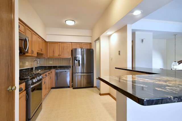 kitchen with stainless steel appliances, backsplash, brown cabinets, dark stone counters, and light floors