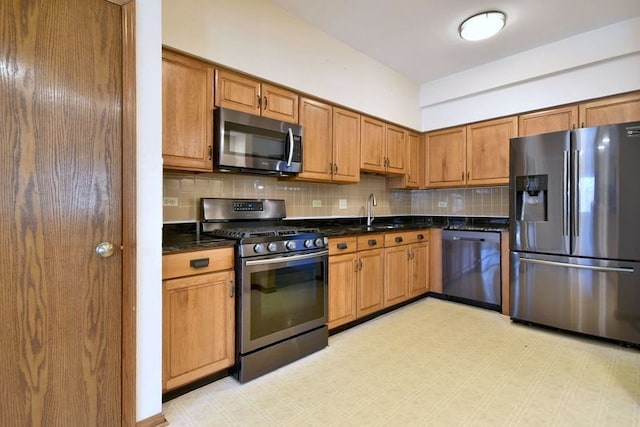 kitchen with brown cabinets, light floors, stainless steel appliances, tasteful backsplash, and a sink