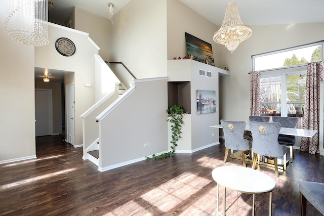 dining area featuring stairs, a notable chandelier, wood finished floors, and high vaulted ceiling