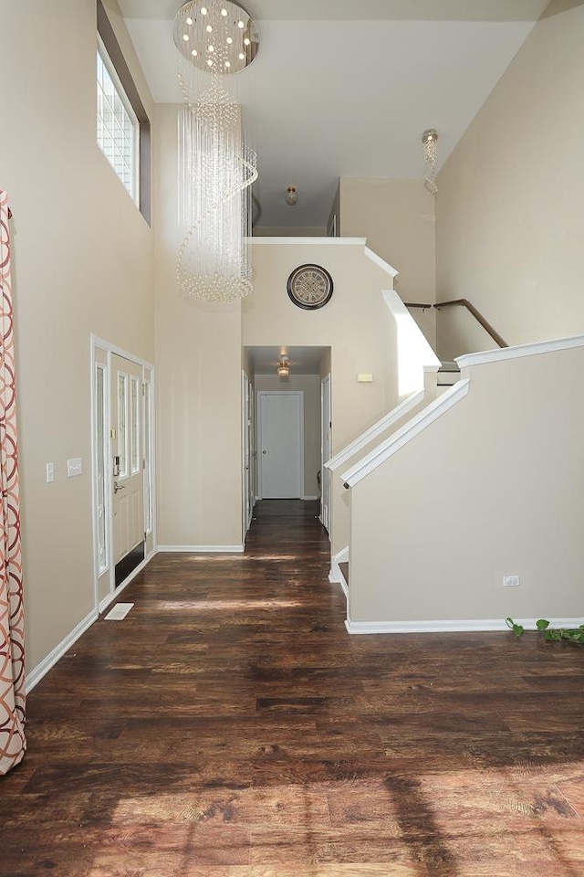 entrance foyer with stairway, wood finished floors, baseboards, a high ceiling, and a chandelier