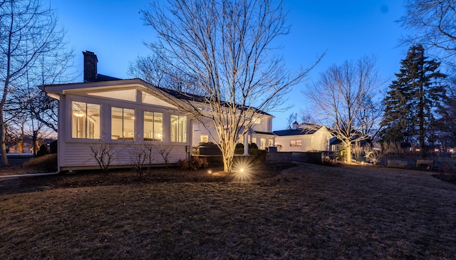 rear view of house featuring a chimney and a sunroom