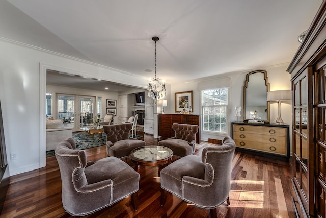 living area featuring a chandelier, baseboards, dark wood finished floors, and ornamental molding