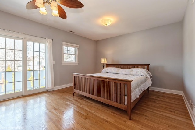 bedroom with access to exterior, a ceiling fan, baseboards, and wood finished floors