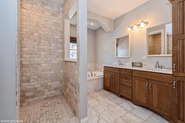 full bath with marble finish floor, double vanity, a sink, and a bath