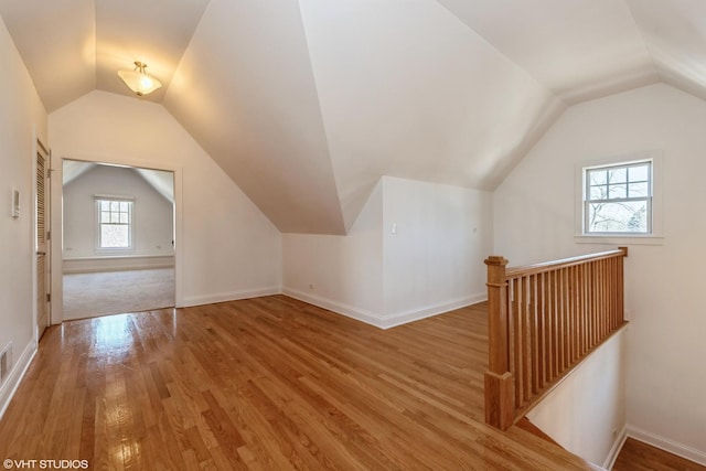 bonus room with lofted ceiling, baseboards, and wood finished floors