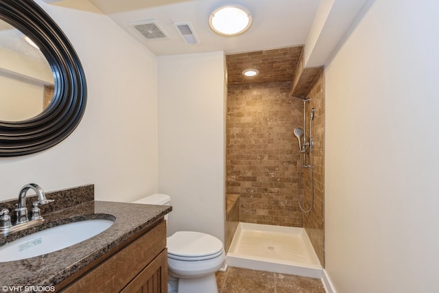 bathroom featuring tiled shower, visible vents, toilet, and vanity