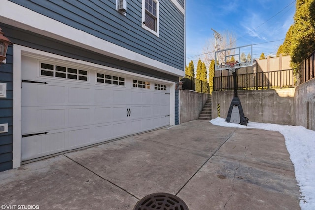 garage with concrete driveway and fence