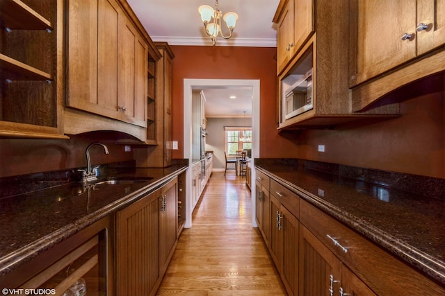 kitchen featuring light wood finished floors, dark stone countertops, crown molding, open shelves, and a sink