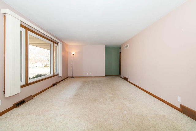 empty room with baseboards, visible vents, and light colored carpet