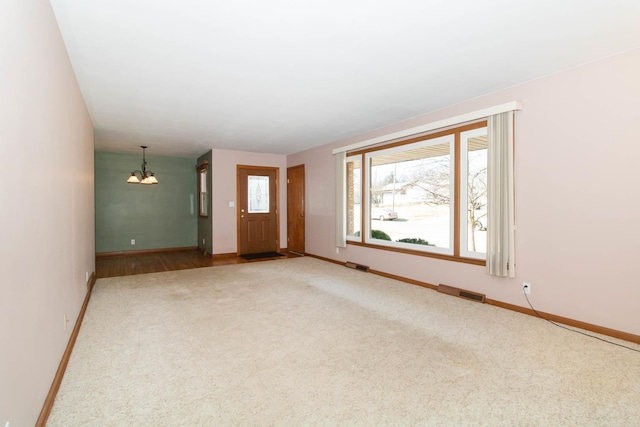 interior space with carpet flooring, visible vents, baseboards, and an inviting chandelier