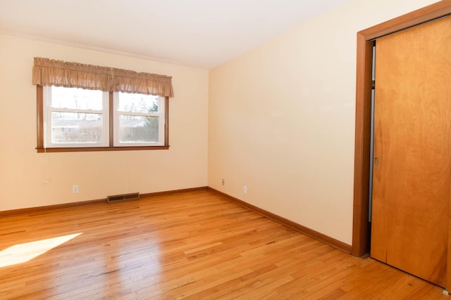 unfurnished room featuring baseboards, visible vents, and light wood finished floors