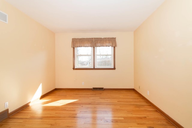 spare room with light wood finished floors, baseboards, and visible vents