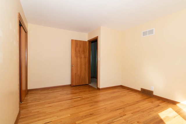 spare room featuring light wood-style floors, baseboards, and visible vents